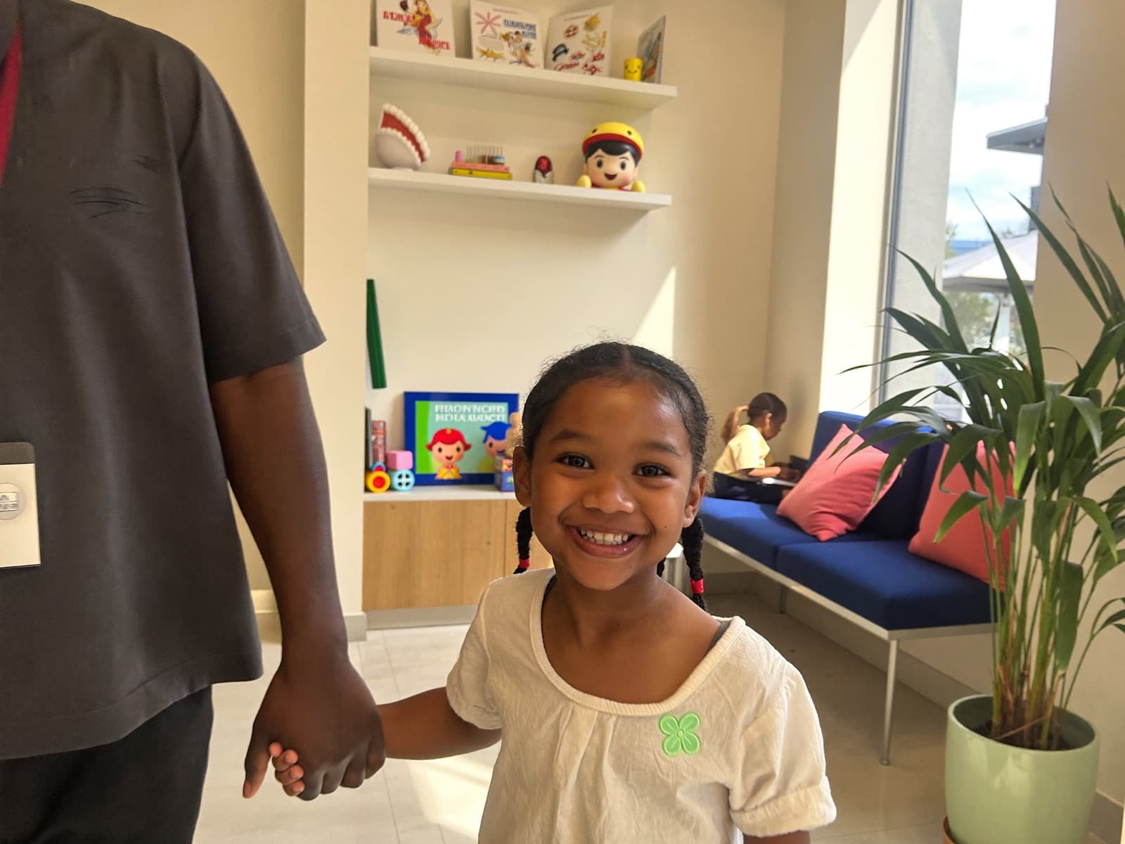 Smiling child arriving hand-in-hand with a parent at the Willow waiting area