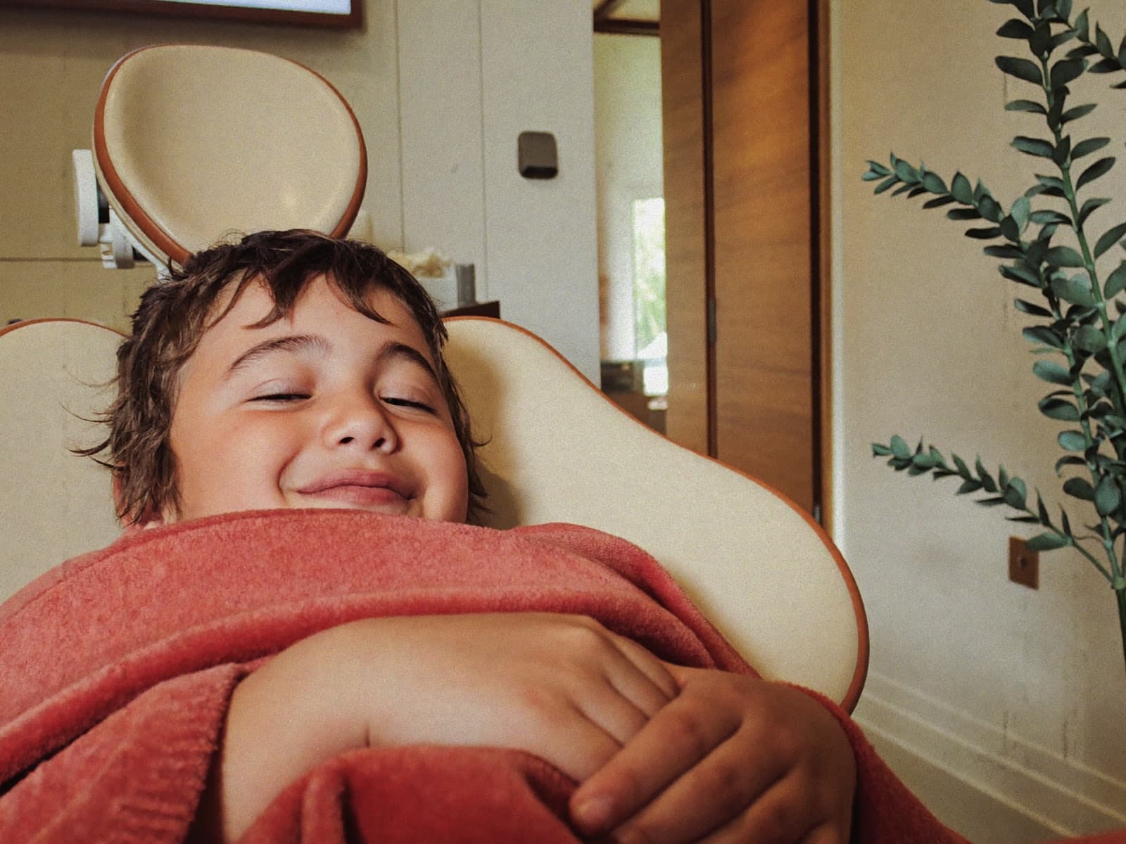 Relaxed child resting comfortably in the dental chair under a cozy blanket